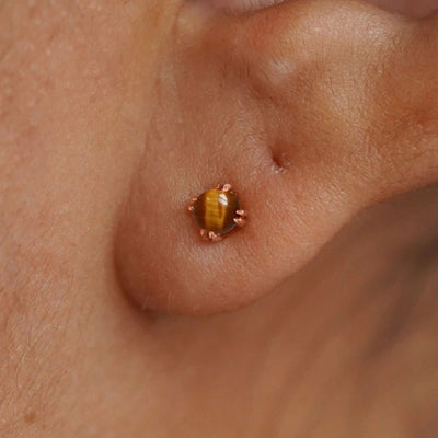 Close up view of a model's ear wearing a 14k rose gold Tiger Eye Earring