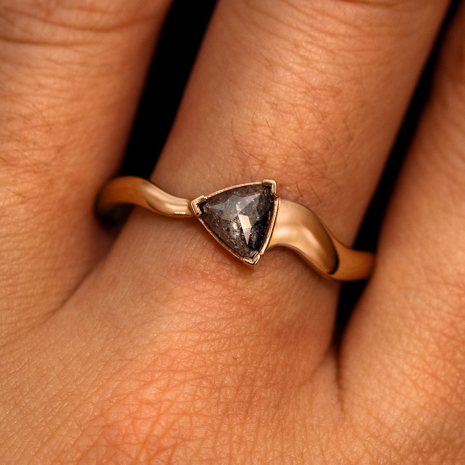 A model's hand wearing a 14k rose gold Trillion Salt and Pepper Diamond Wavy Ring