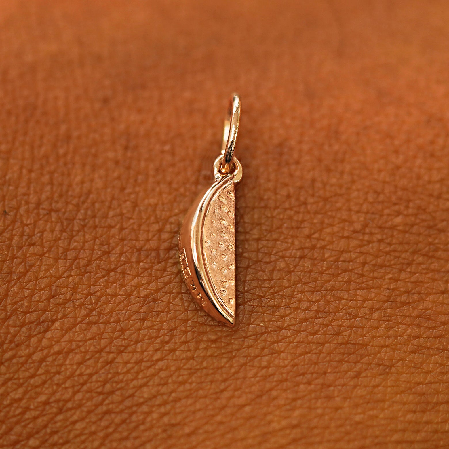 A solid 14k rose gold Watermelon Charm resting on the back of a model's hand