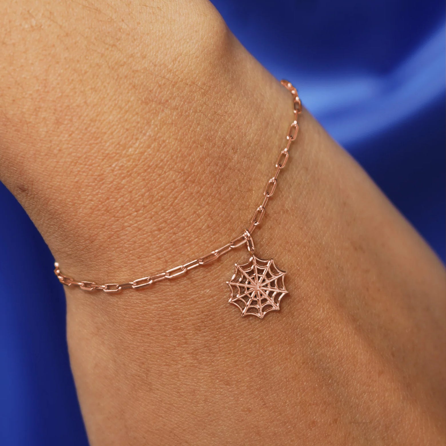 Close up view of a model's wrist wearing a rose gold Spider Web Charm on a Butch Chain Bracelet