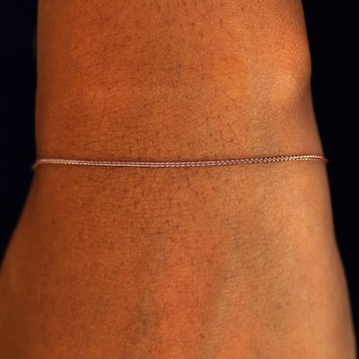 A model's wrist wearing a solid 14k rose gold Wheat Chain