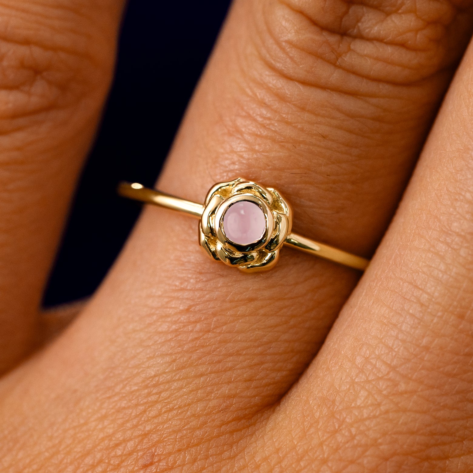 A solid 14k yellow gold Rose Quartz Gemstone Flower Ring on a model's finger