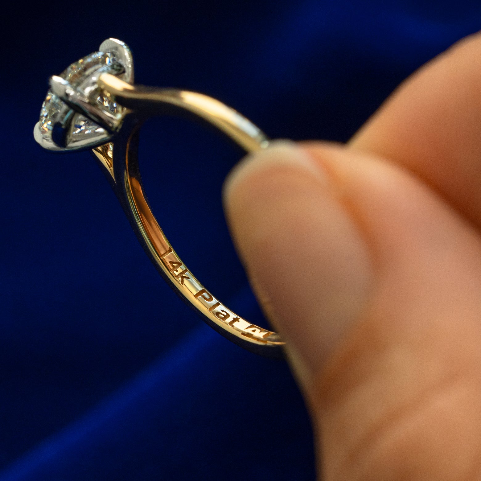A model holding a Round Lab Diamond Cathedral Set Ring tilted to show the platinum and gold stamps on the inside of the band