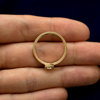 A round diamond hexagon signet ring laying flat in a models palm to show the thickness of the band