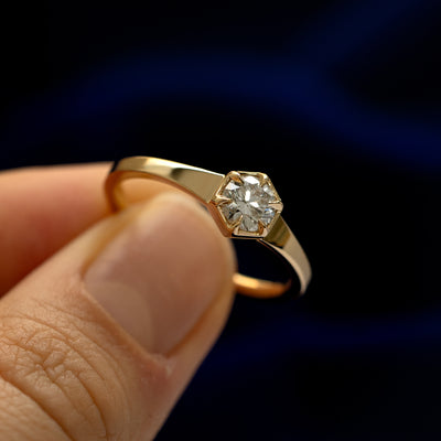 A model holding a round diamond hexagon signet ring tilted to show the claw setting around the stone