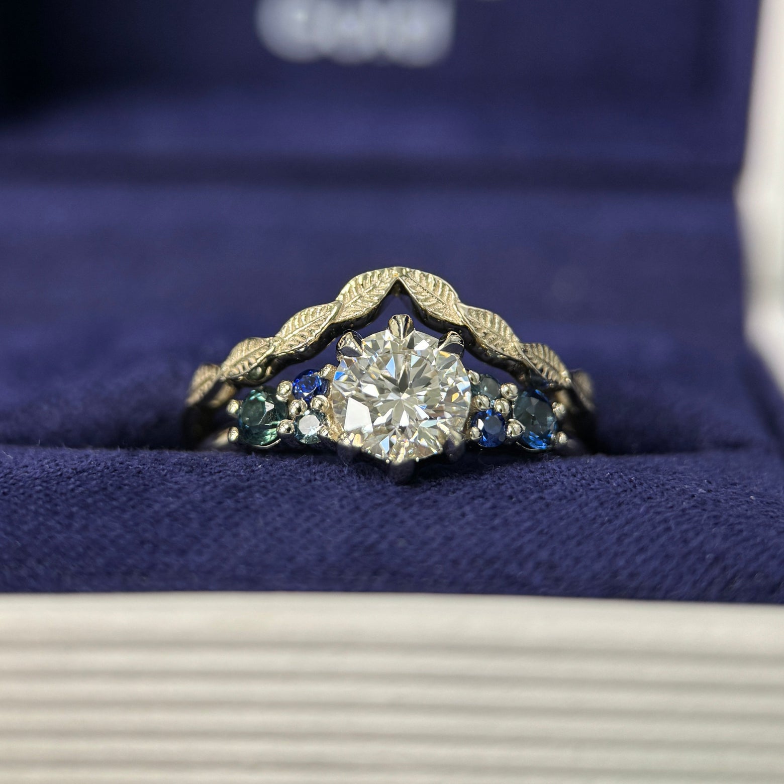 14k Champagne Gold & 6mm Round Lab Diamond & 2pc 2.7mm Customer’s Sapphires & 4pc Tiny Teal/Blue Sapphires Custom Ring & 14k Champagne Gold Nesting Leaves Custom Band