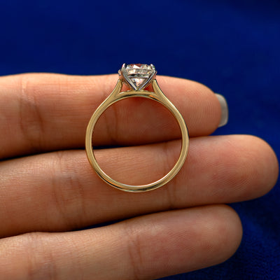 A yellow gold Round Lab Diamond Cathedral Set Ring in a model's hand showing the thickness of the band