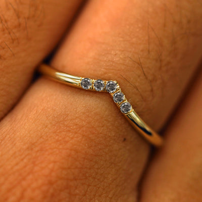 Close up view of a model's fingers wearing a 14k yellow gold Salt and Pepper Diamond Chevron Band