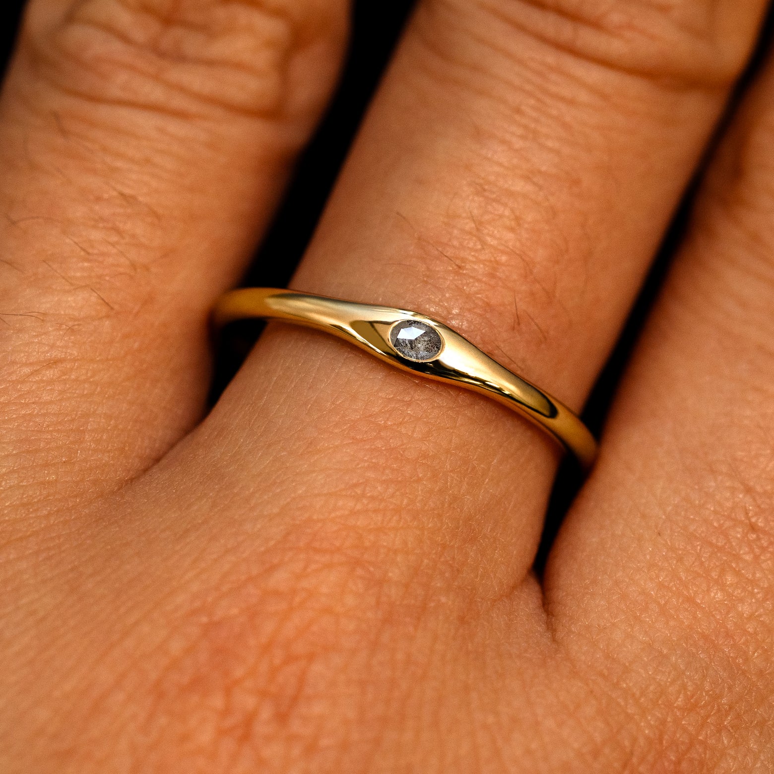 A 14k yellow gold Flush Set Oval Salt and Pepper Diamond Ring on a model's finger