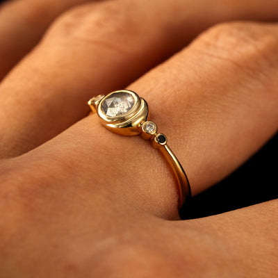 Side view of a solid 14 karat gold Rose Cut Salt and Pepper Diamond Moon Ring on a model's finger