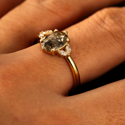 Side view of a solid 14 karat gold Oval Salt and Pepper Diamond Heart Prong Ring on a model's finger