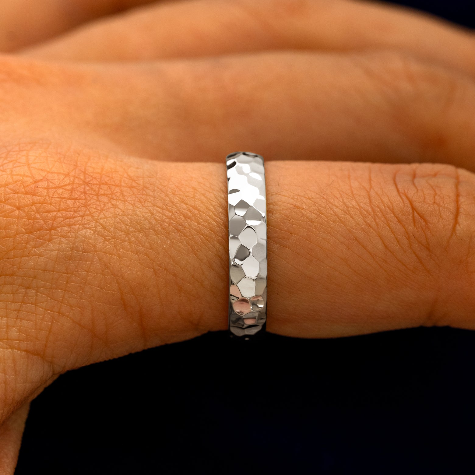 Side view of a Silver Curvy Hammered Band on a model's finger
