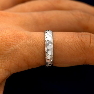 Side view of a Silver Curvy Hammered Band on a model's finger