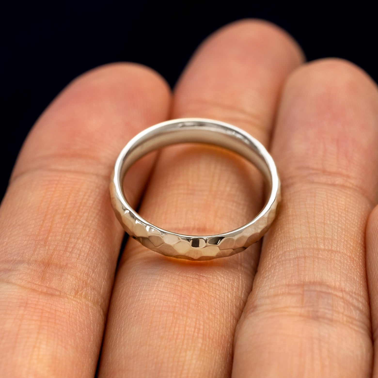 A 925 Silver Curvy Hammered Band resting on a model's fingers to show the thickness of the band