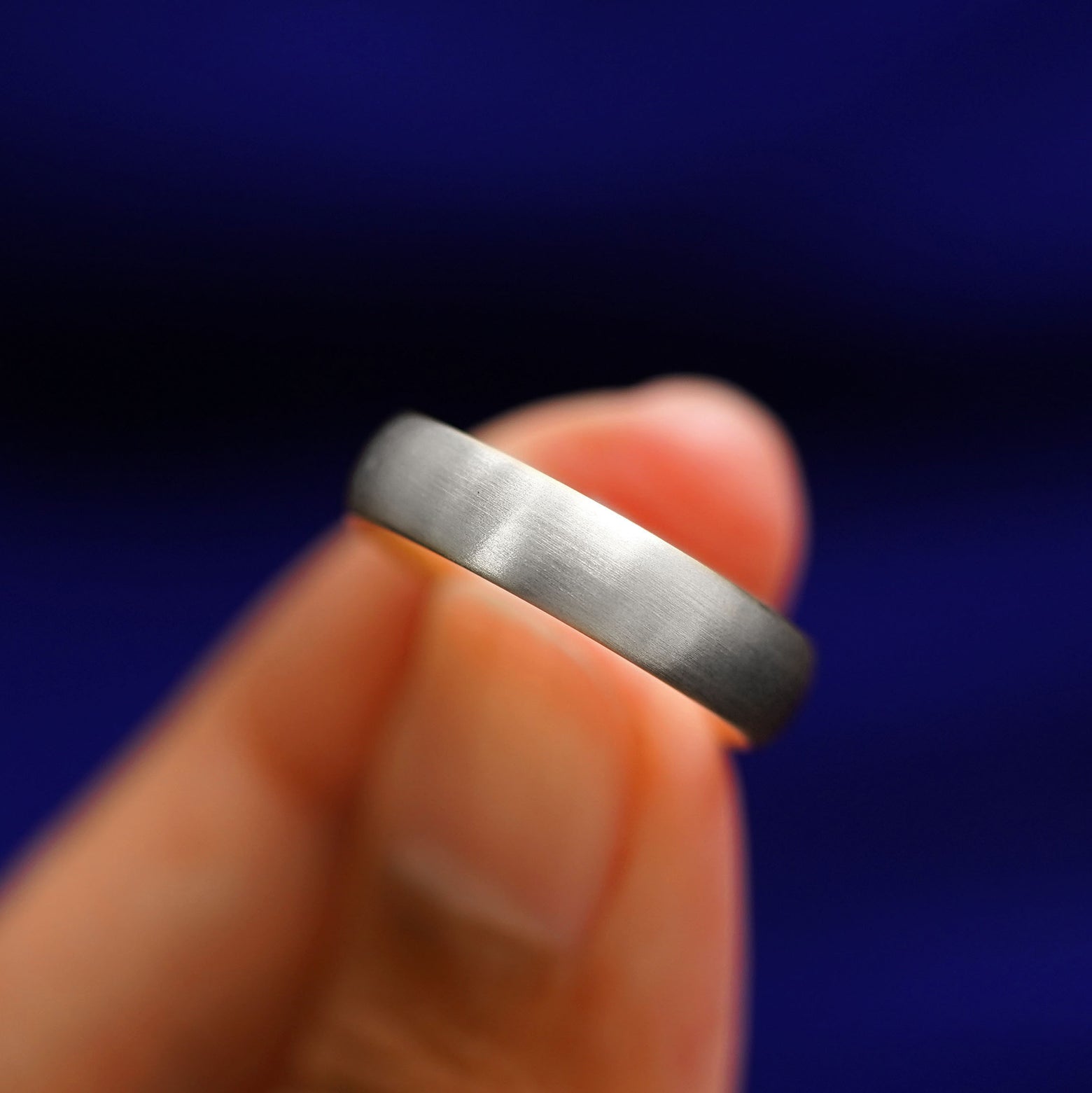 A model holding a Silver Curvy Matte Band tilted to show the details of the matte finish