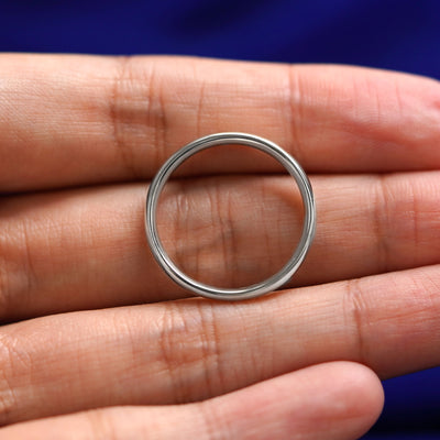 A Sterling Silver Curvy Mirror Band resting on a model's fingers to show the thickness of the band