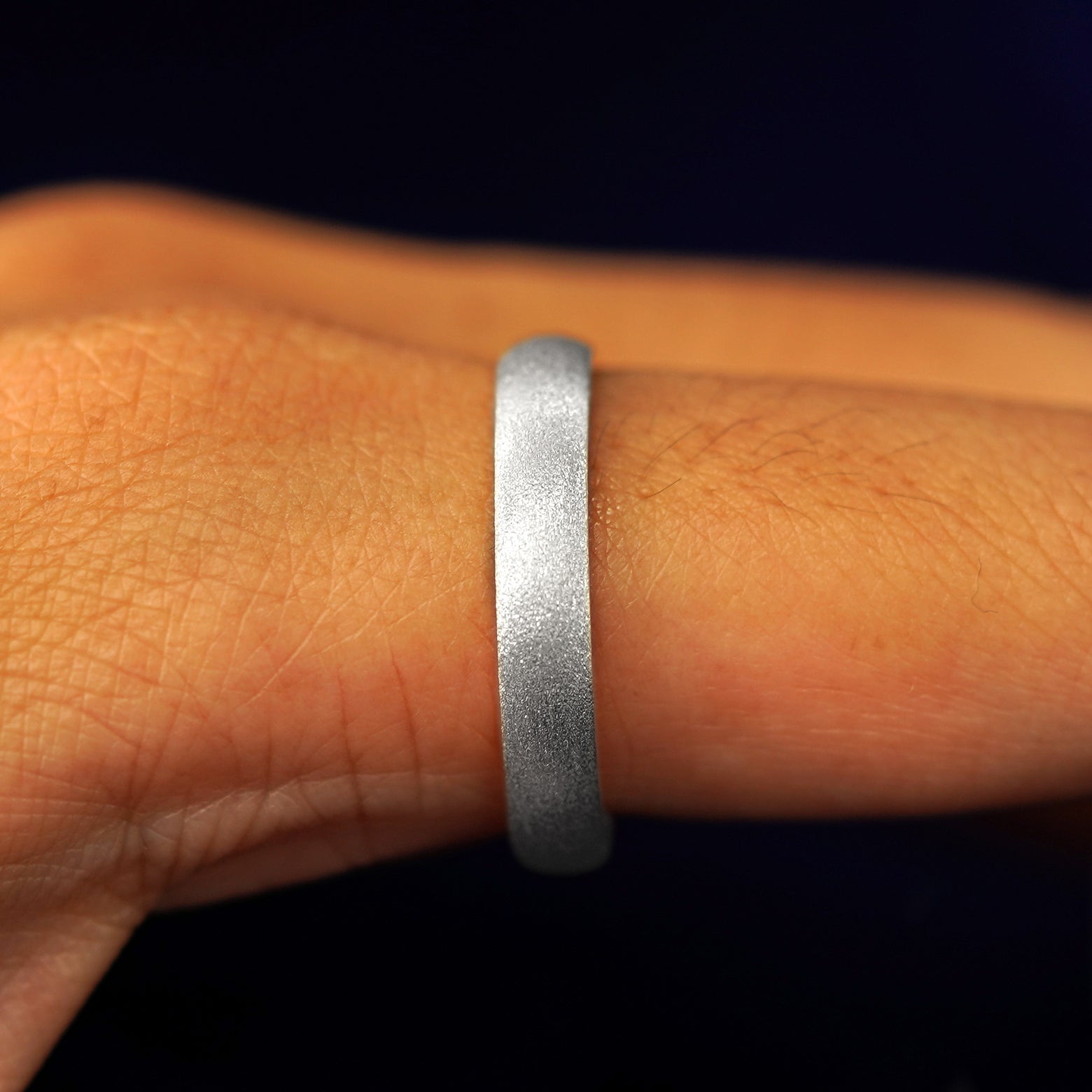 Side view of a Sterling Silver Curvy Stardust Band on a model's finger