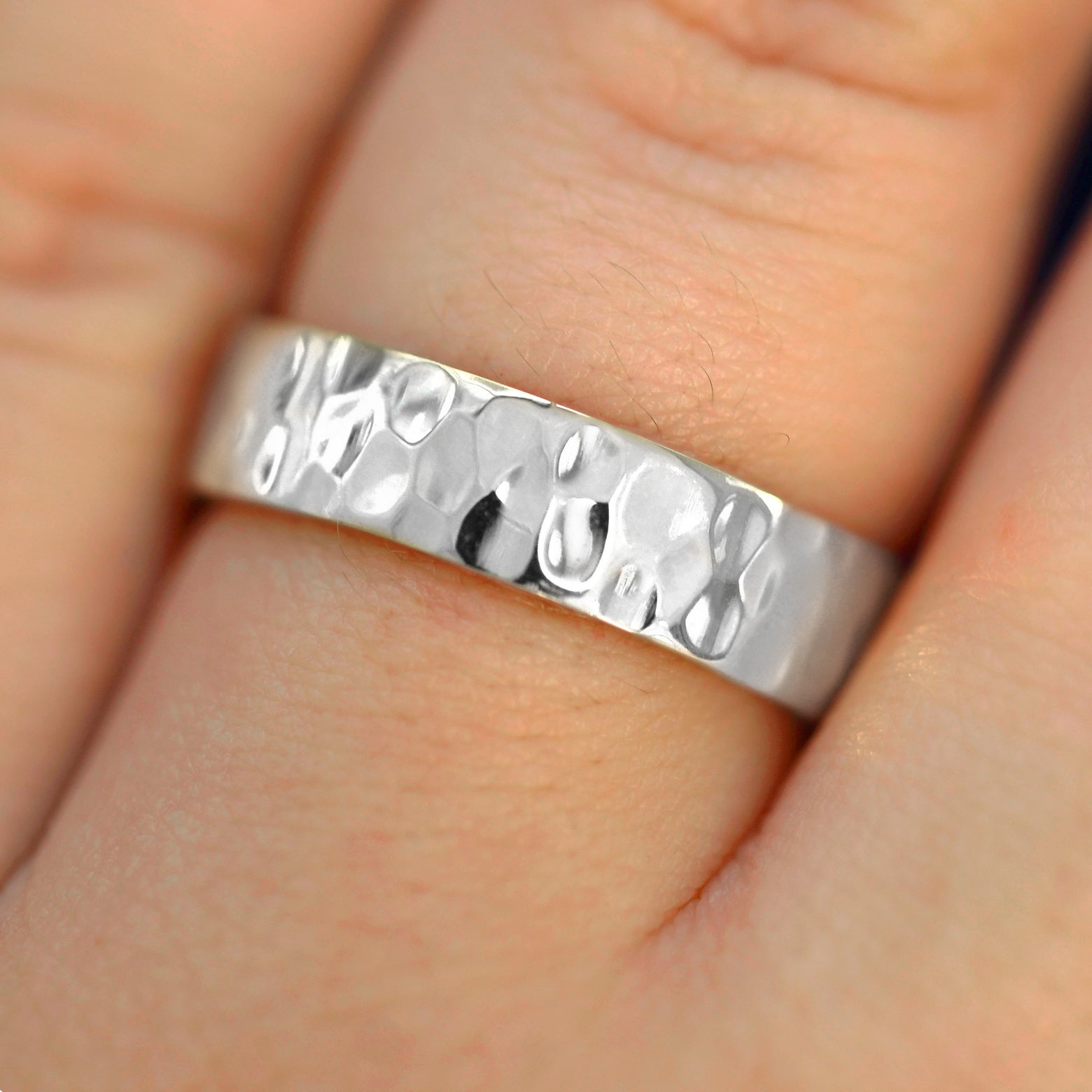 Close up view of a model's hand wearing a 4mm 925 Silver Industrial Hammered Band