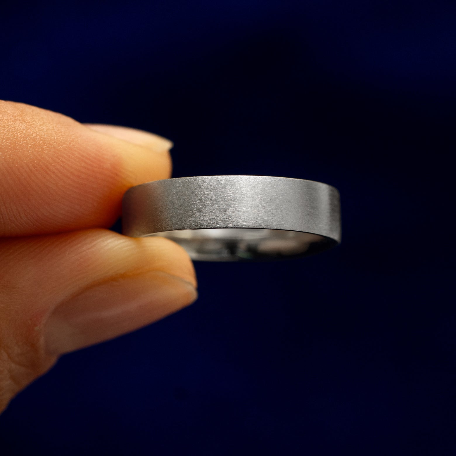 A model holding a Sterling Silver Industrial Matte Band tilted to show the details of the matte finish