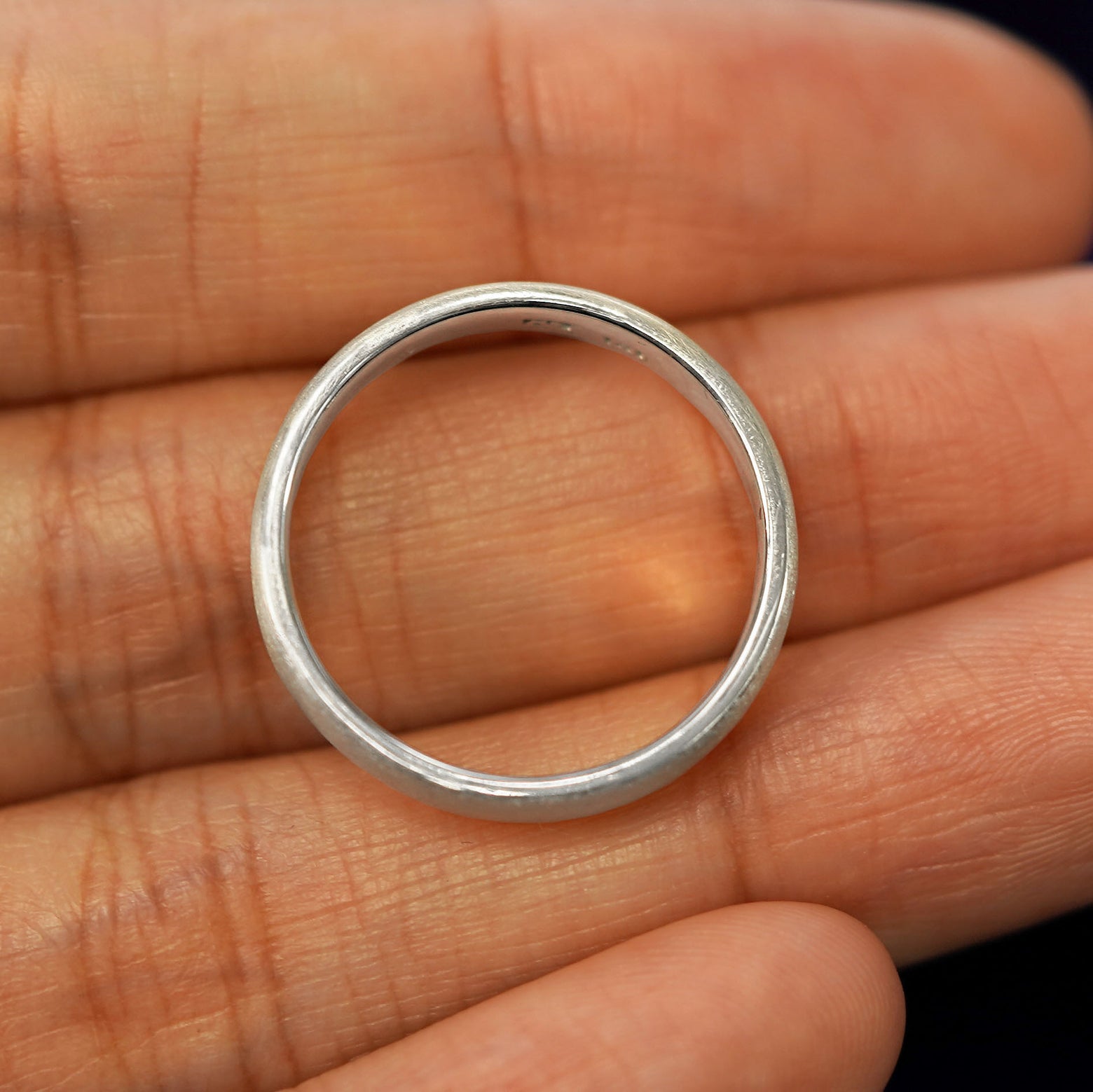 A silver Mix Matte Band in a model's hand showing the thickness of the band