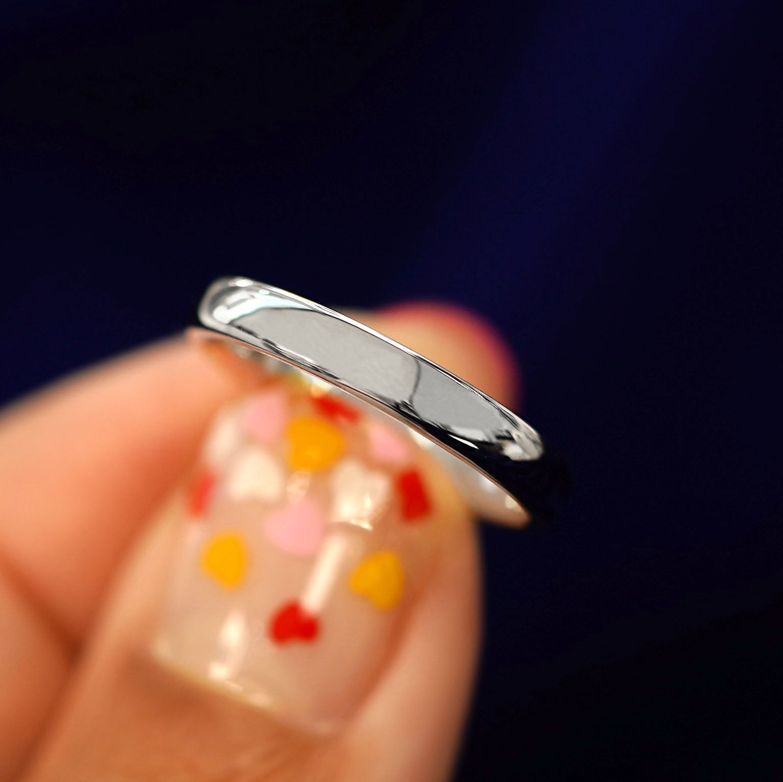 A model holding a 925 Silver Mix Mirror Band tilted to show the side of the ring