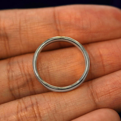 A silver Mix Mirror Band in a model's hand showing the thickness of the band