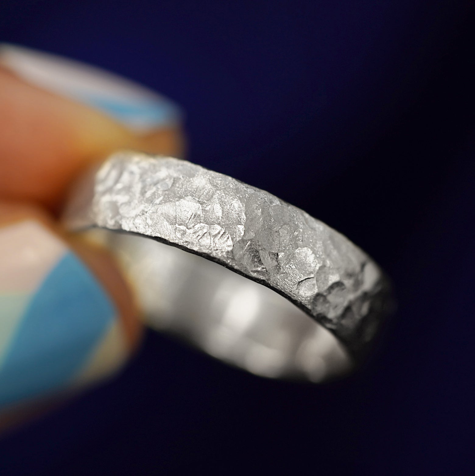 A model holding a Sterling Silver Mix Organic Band tilted to show the side of the ring