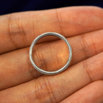 A 925 sterling silver Mix Stardust Band in a model's hand showing the thickness of the band