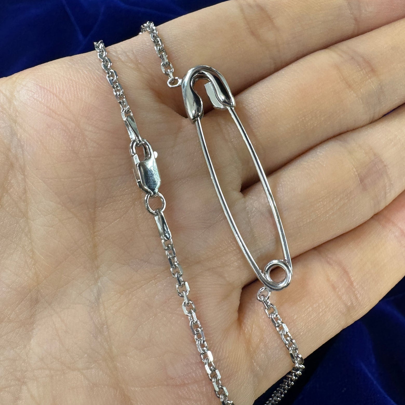 Silver pin cable chain necklace resting on models hand