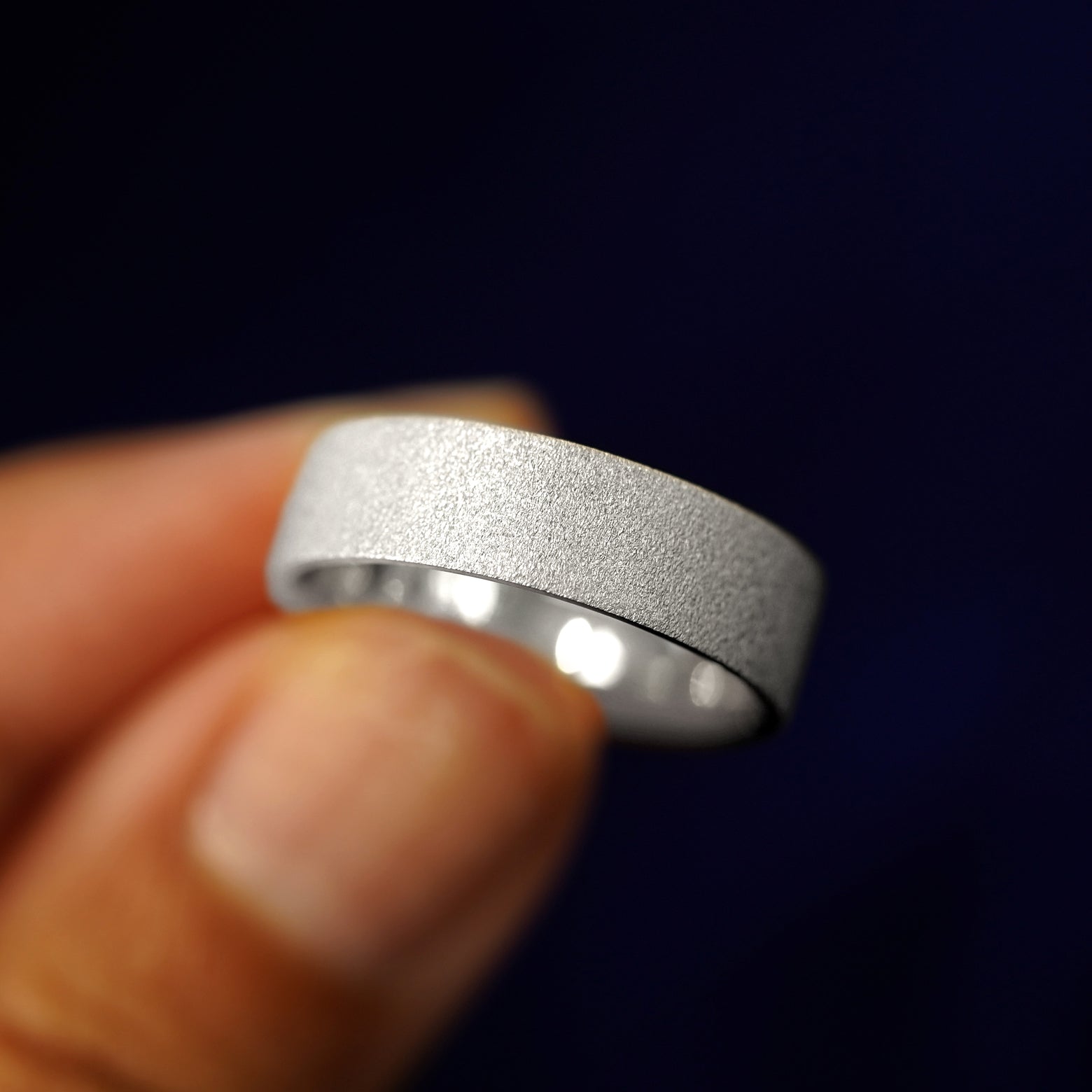 A model holding a Silver Industrial Stardust Band tilted to show the details of the star dust finish