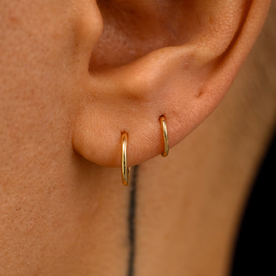 A models ear wearing a small seamless and a mini seamless huggie in two lobe piercings