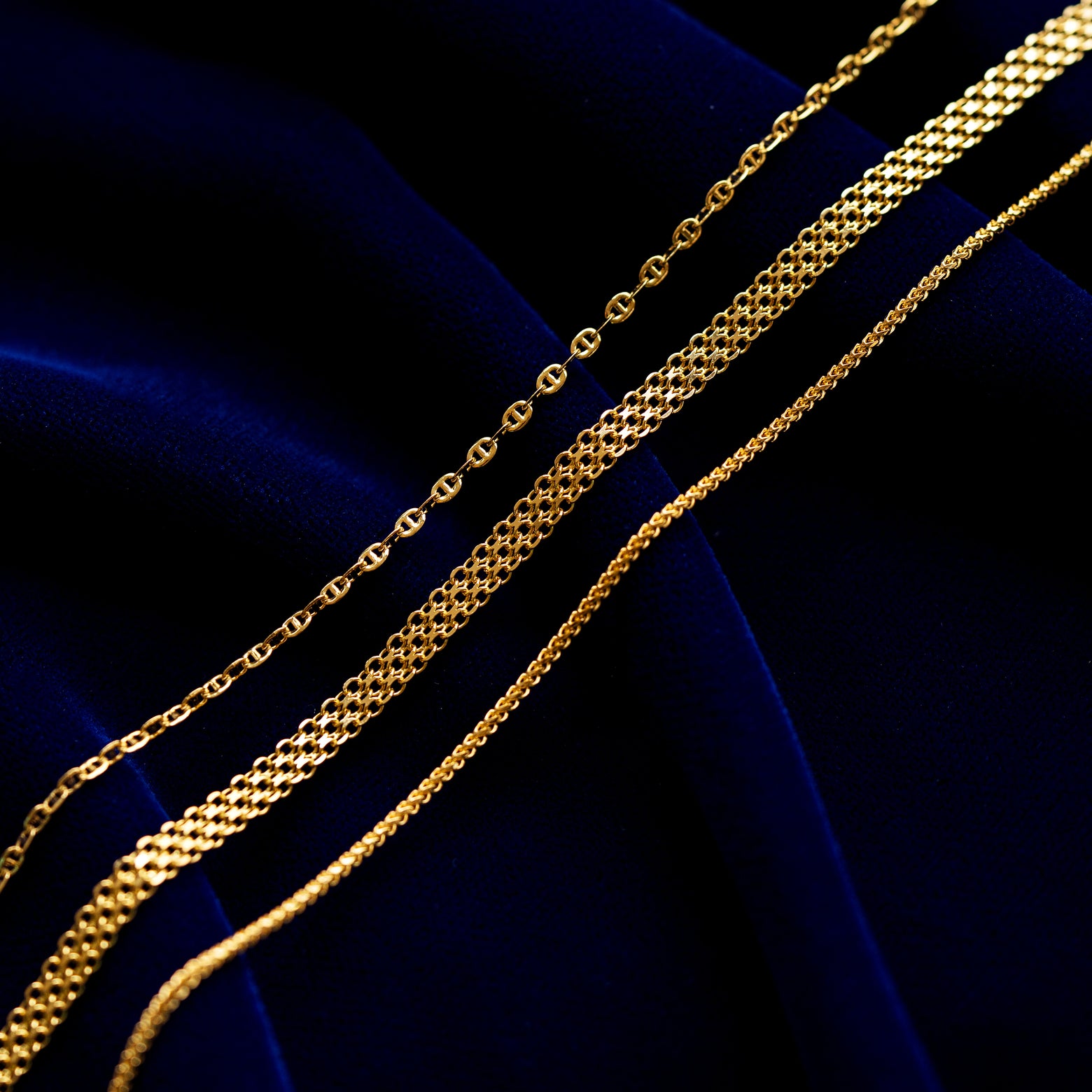 Flat Mariner chain, Bismark Chain, and Mini Franco Chain on a dark blue cloth background