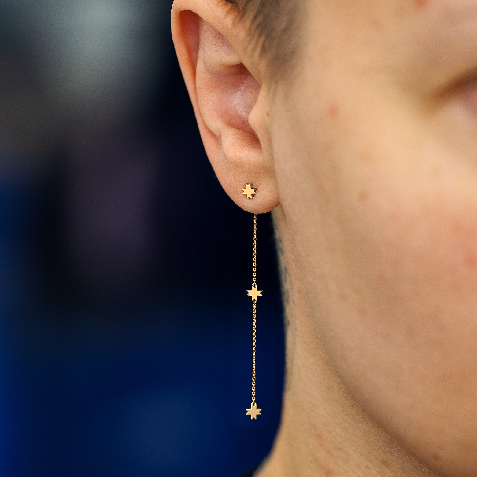 A model wearing a 14k yellow gold 8 pointed star extender with an 8 pointed star stud earring