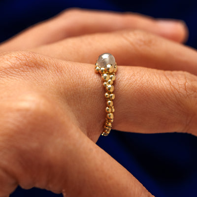 Side view of a models finger wearing a 14k gold diamond fidget bubbles ring to show the height of the ring