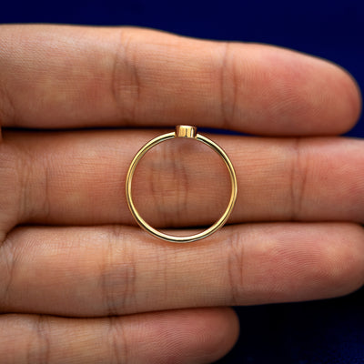 A yellow gold Garnet Ring in a model's hand showing the thickness of the band