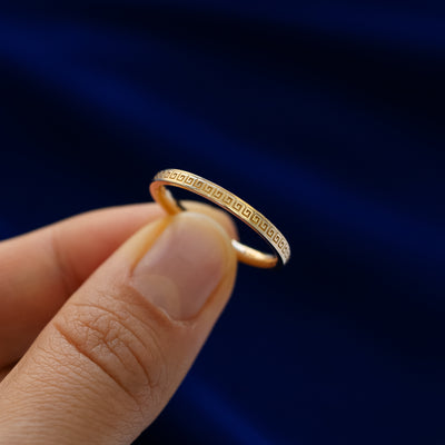 A model holding a geometric grass band between two fingers to show engraved pattern details