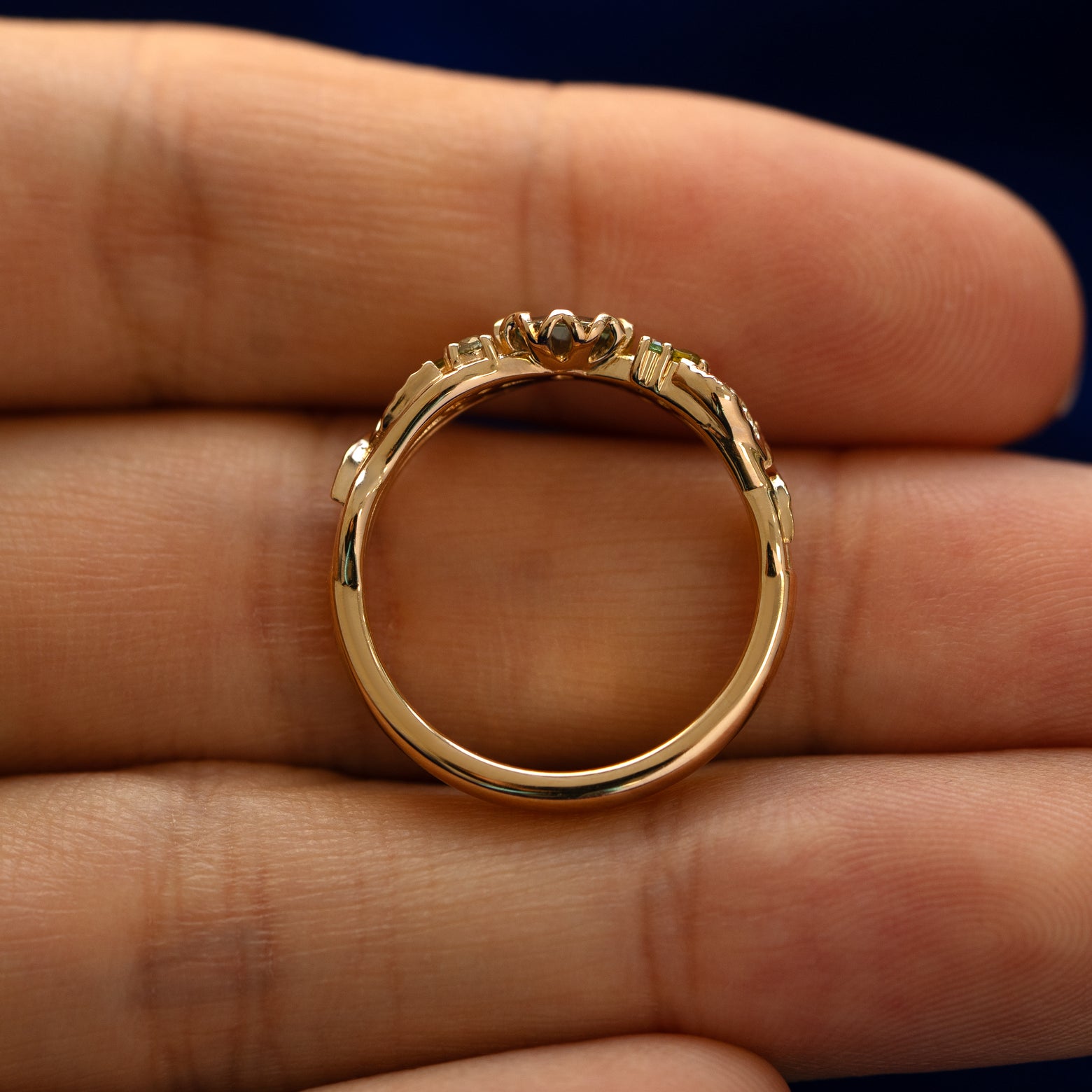 A yellow gold Green Sapphire Leaves and Vines Ring in a model's hand showing the thickness of the band