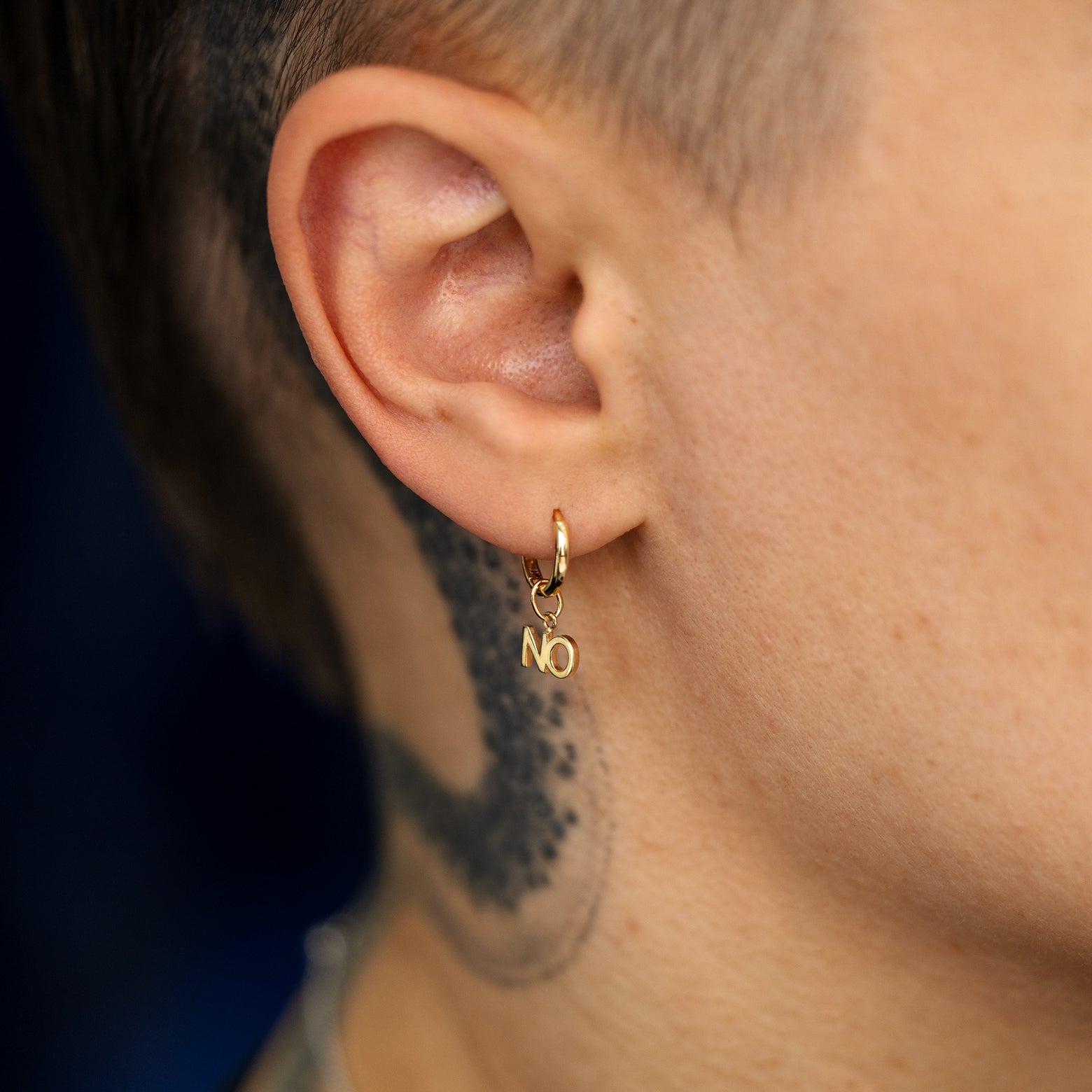 Close up view of a model's ear wearing a solid gold No Charm on a Curvy huggie hoop earring