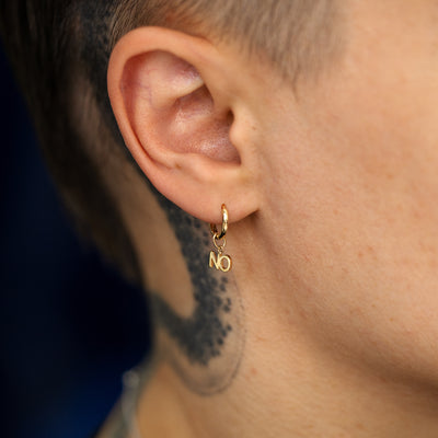 Close up view of a model's ear wearing a solid gold No Charm on a Curvy huggie hoop earring