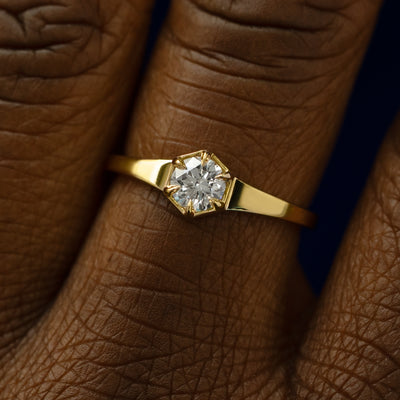 Close up view of a models fingers wearing a solid gold round diamond hexagon signet ring