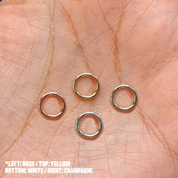 Four versions of the Mini Seamless Huggie Hoop / Piercing shown in options of rose, yellow, champagne, and white gold