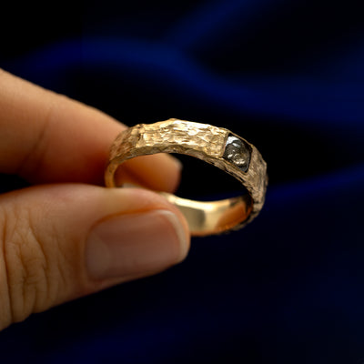 A model holding a square diamond organic band tilted to show the details of the stone and the setting