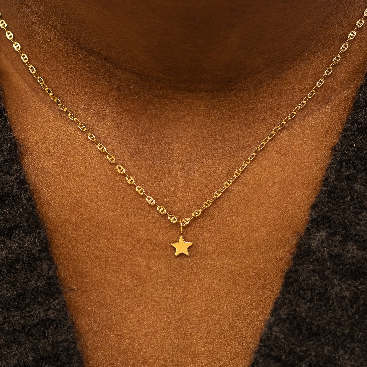 A model wearing a solid gold star charm on a mariner chain