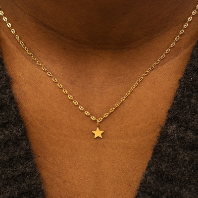 A model wearing a solid gold star charm on a mariner chain