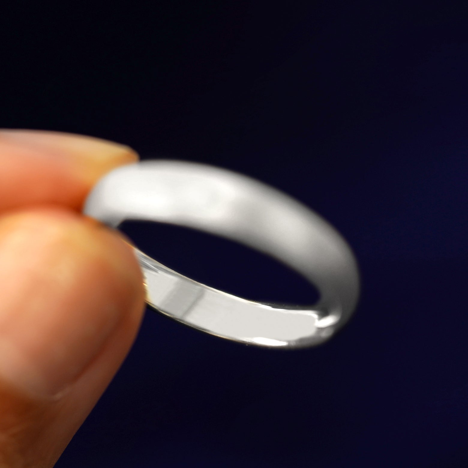 A model holding a Sterling Silver Curvy Stardust Band tilted to show the inside of the ring
