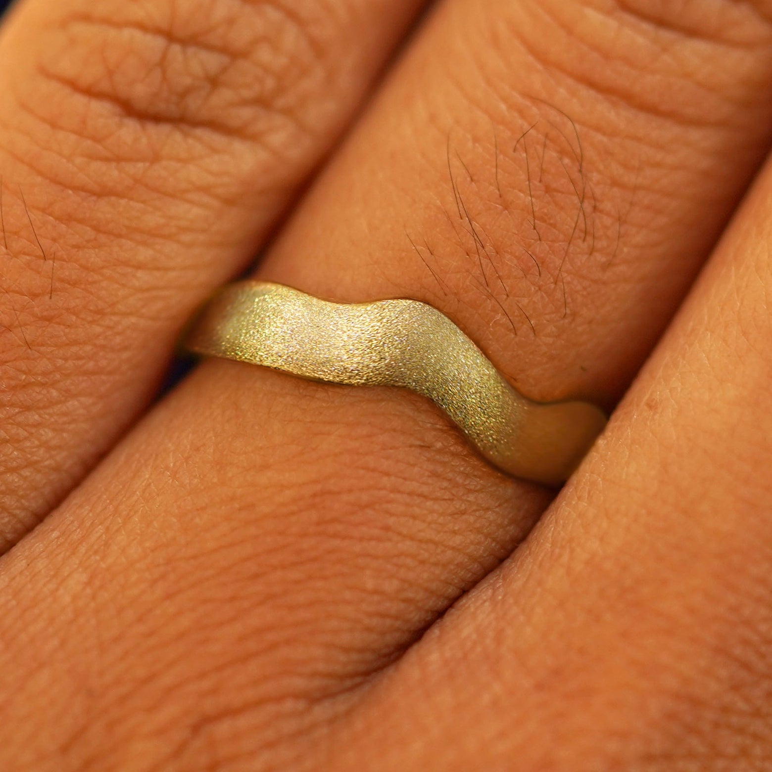 Close up view of a model's fingers wearing a 14k Stardust Liquid Band