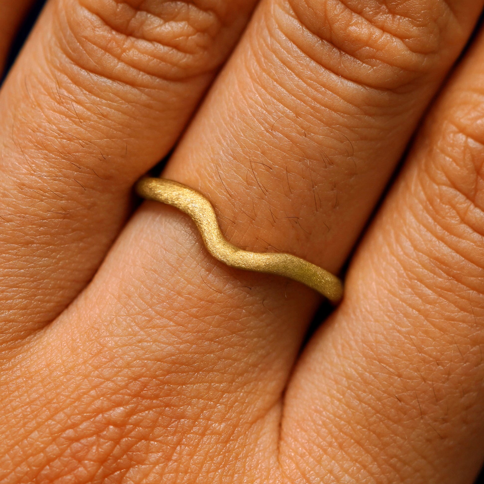 Close up view of a model's hand wearing a stardust thin liquid band