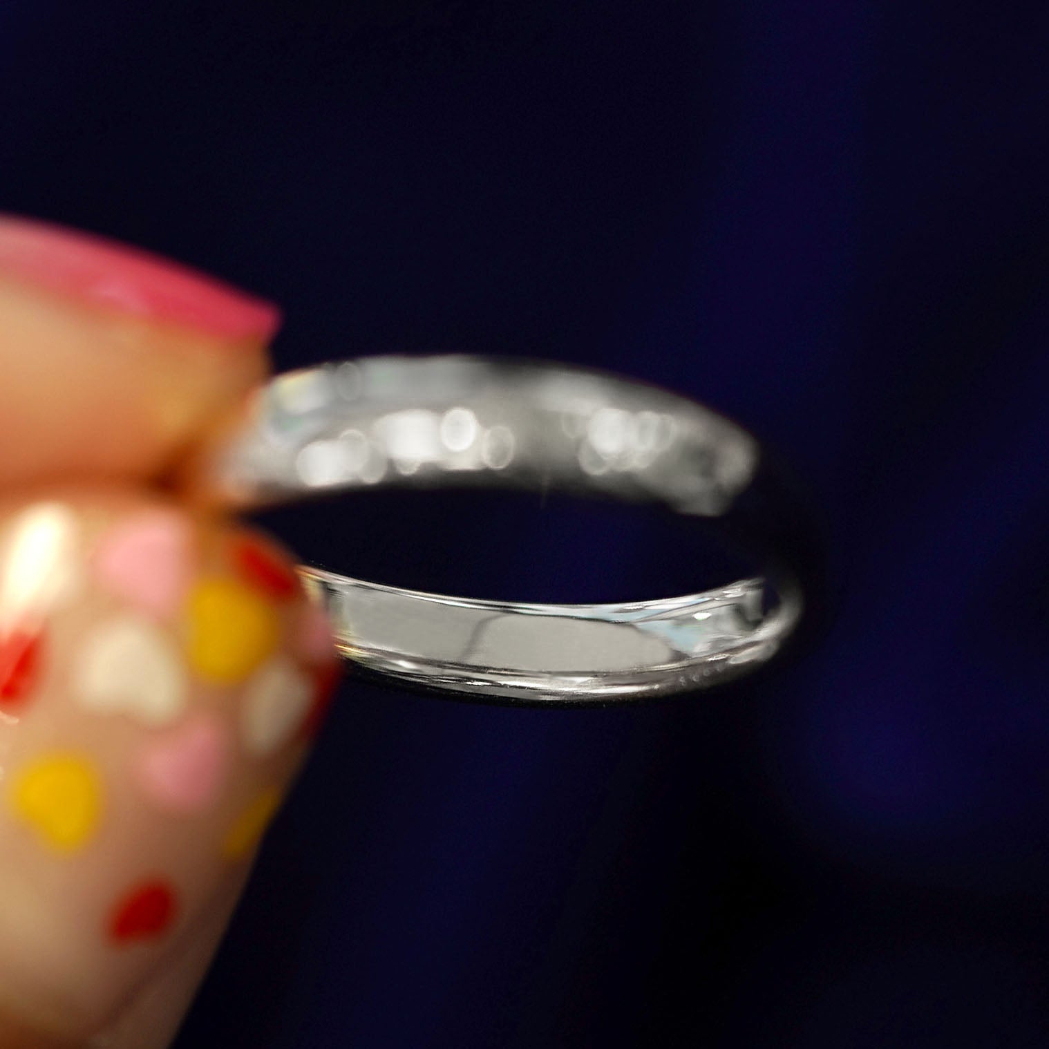 A model holding a solid silver Mix Mirror Band tilted to show the inside of the band