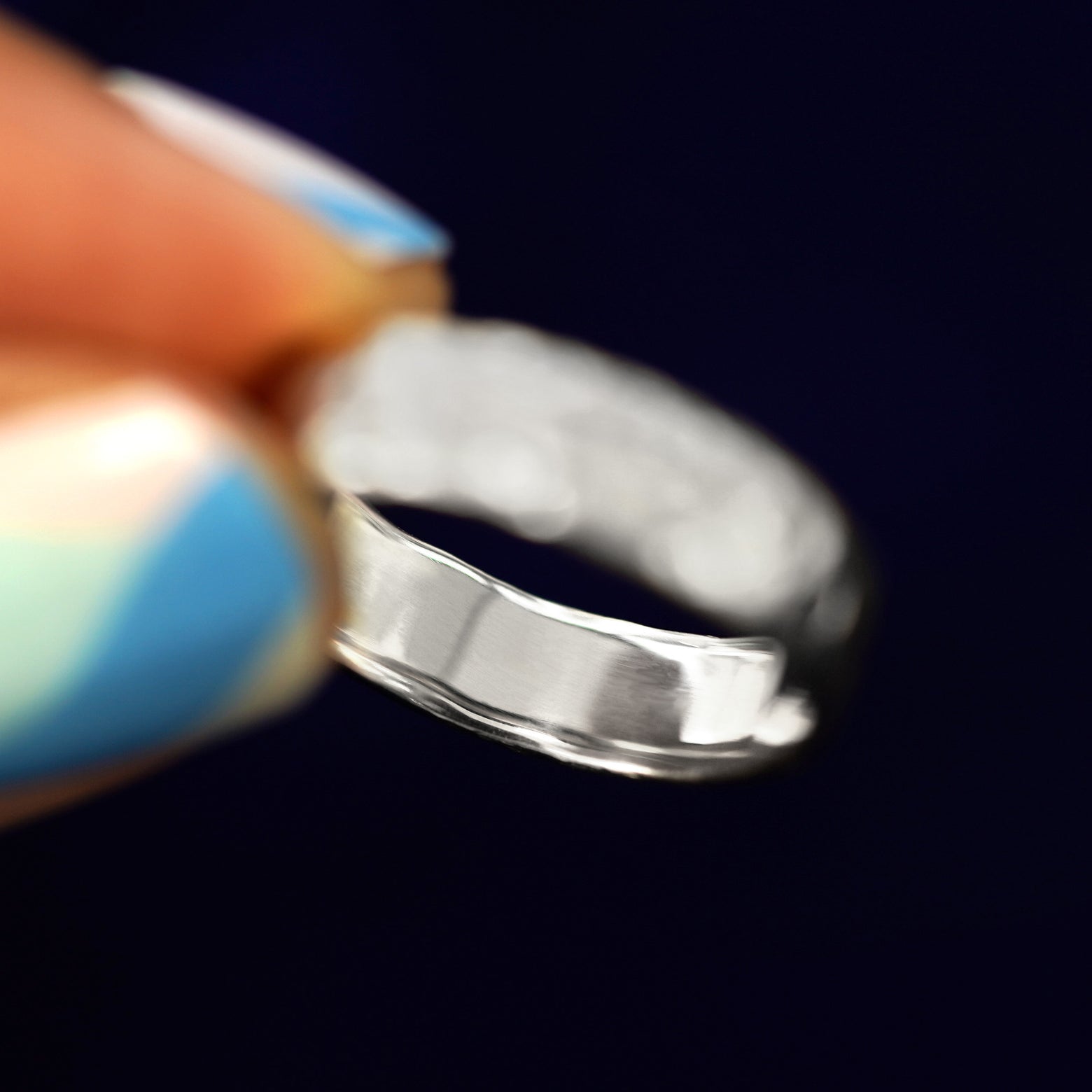 A model holding a solid silver Mix Organic Band tilted to show the inside of the band