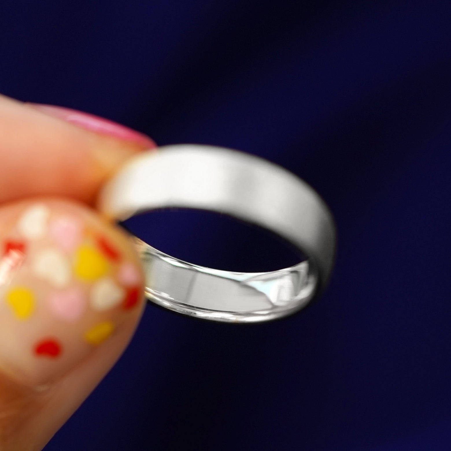 A model holding a solid silver Mix Stardust Band tilted to show the inside of the band